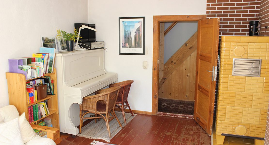 Das Ferienhaus-Uckermark Wohnzimmer mit Klavier und gemütlichem Kachelofen durch die Winterferien. Selbstversorger Urlaub im Boitzenburger Land schon ab 29,- Euro pro Tag
